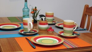 Un tavolo da pranzo con piatti colorati, tazze e una bottiglia.