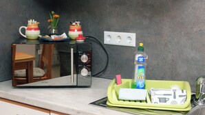 Un piano di lavoro in cucina con un forno a microonde, un portascopri verde e una bottiglia di detergente.