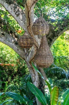 Surrounded by lush greenery, this tree features three woven hanging baskets.