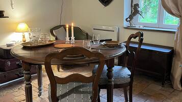 Un comedor con mesa de madera, sillas, televisor montado en la pared y una ventana con cortinas.
