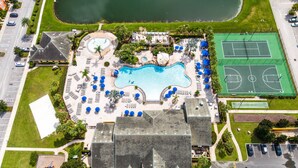 Vue aérienne d’un complexe hôtelier doté d’une piscine, de courts de tennis et d’un parking.