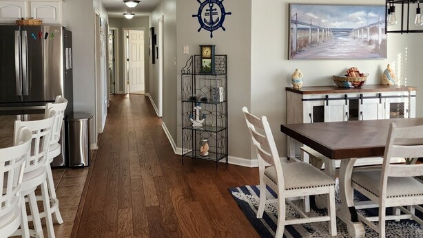 A kitchen with a refrigerator, a dining table with chairs, a hallway with a door, and a wall with a nautical-themed decoration. - WW Condo 1.5 blks to beach and boardwalk. Walk to shops, restaurants and CC. (Wildwood)