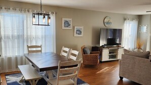 A living room with a dining area, wooden flooring, a TV, and a sofa. - WW Condo 1.5 blks to beach and boardwalk. Walk to shops, restaurants and CC. (Wildwood)