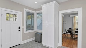 A room with a door, a window with blinds, a tall white cabinet, and a table with chairs. - Spacious Home on Gervais | 4BR 2BA | Downtown (Columbia)