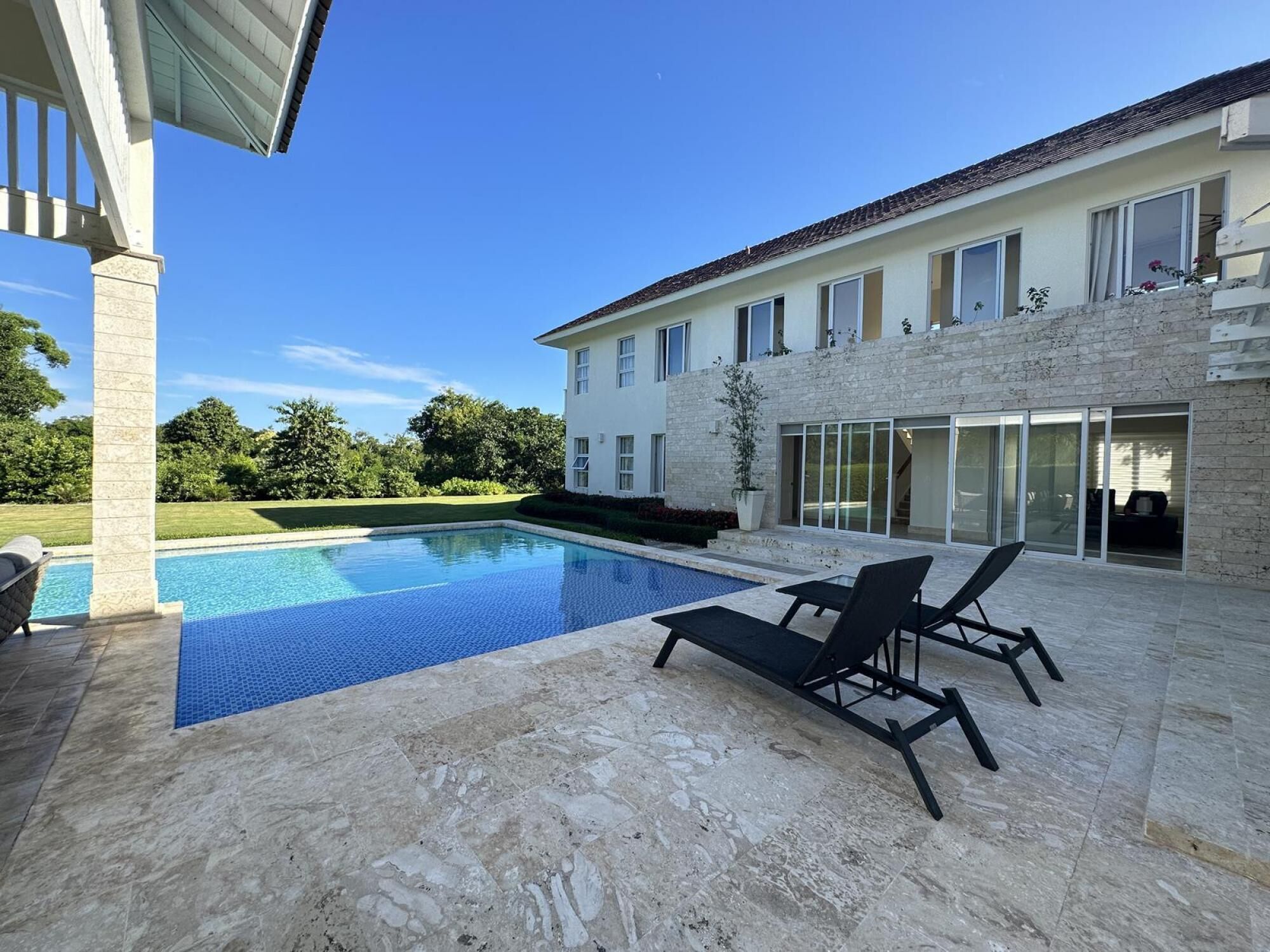A modern house with a swimming pool, outdoor seating, and a well-maintained lawn.