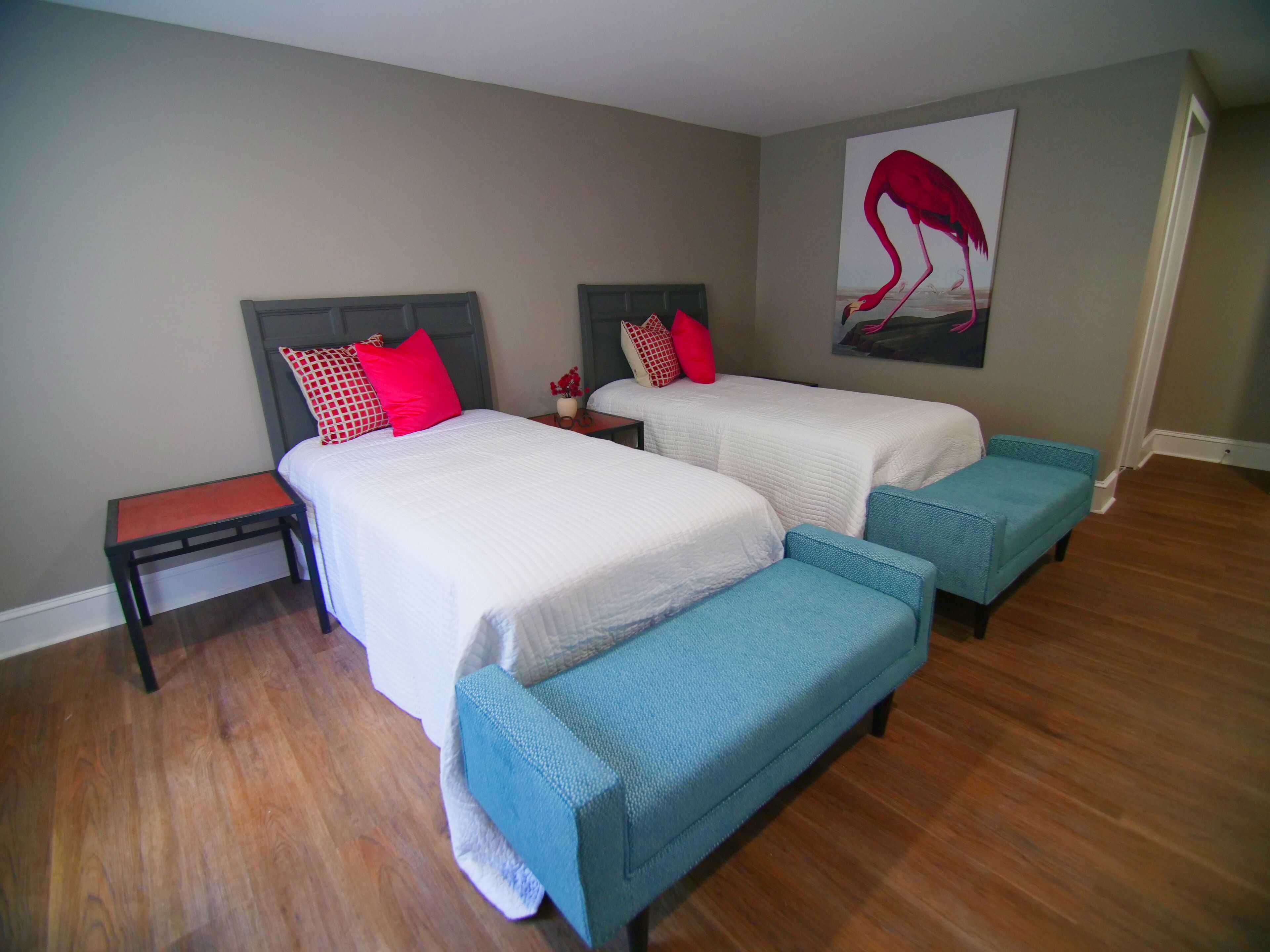A bedroom with two beds, a nightstand, and a bench.