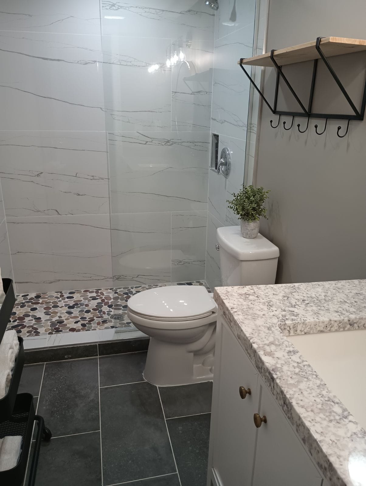 A modern bathroom with a shower, toilet, and marble-tiled floor.