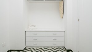 A white bathroom with a herringbone-patterned floor, a towel rack, and a white vanity with drawers.