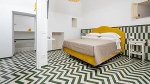 A room with a bed, a mirror, a hanging light fixture, and a patterned floor.
