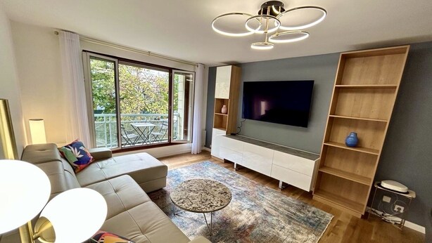 Un salon moderne comprenant un canapé, une table basse, un téléviseur et une bibliothèque.