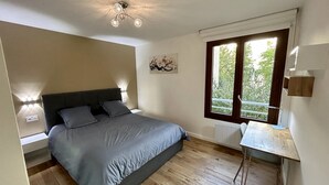 Une chambre à coucher avec un lit, des lampes de chevet, une fenêtre donnant sur un beau paysage et une petite table.