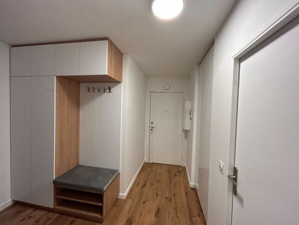 A hallway with a wooden bench, a coat rack, and a door with a light switch. - Beautifully renovated 92 m², 4-room apartment (Charenton-le-Pont)