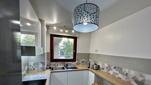 Une cuisine moderne avec une fenêtre, un évier, une cuisinière et un tabouret en bois.