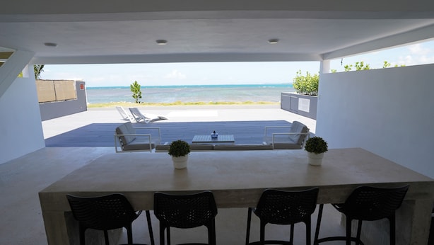 An outdoor patio with a view of the sea, a table with chairs, and two potted plants. - Villa Picuas R in Rio Grande Magical place (Río Grande)