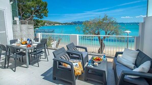 A terrace with outdoor furniture, a dining table set, and a view of the sea.