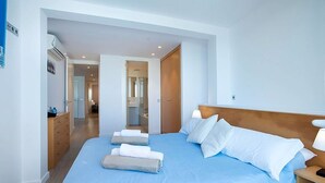 A hotel room with a large bed, a wooden headboard, a nightstand with a lamp, and a wooden dresser with a mirror.