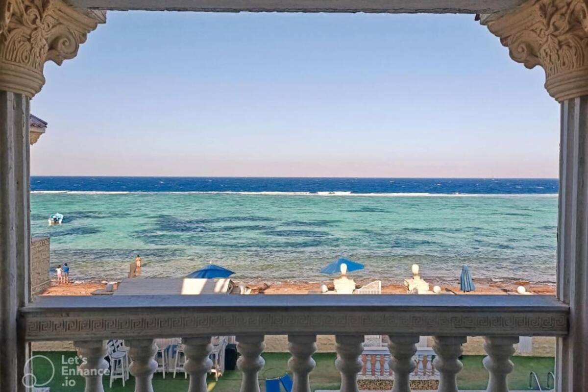 Un balcón con vista al mar, zona de piscina y un bar.