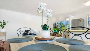 A dining area with a wooden table, black chairs, and a white orchid in a white pot.