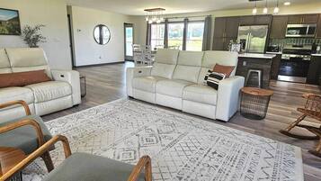 A spacious living area with a sofa, chairs, a dining table, and a kitchen with modern appliances.