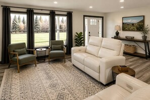 Una sala de estar con un sofá color beige, dos sillones, una mesa de centro y una alfombra estampada.