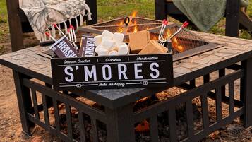 A campfire with a sign reading 'S'MORES' and various snacks.