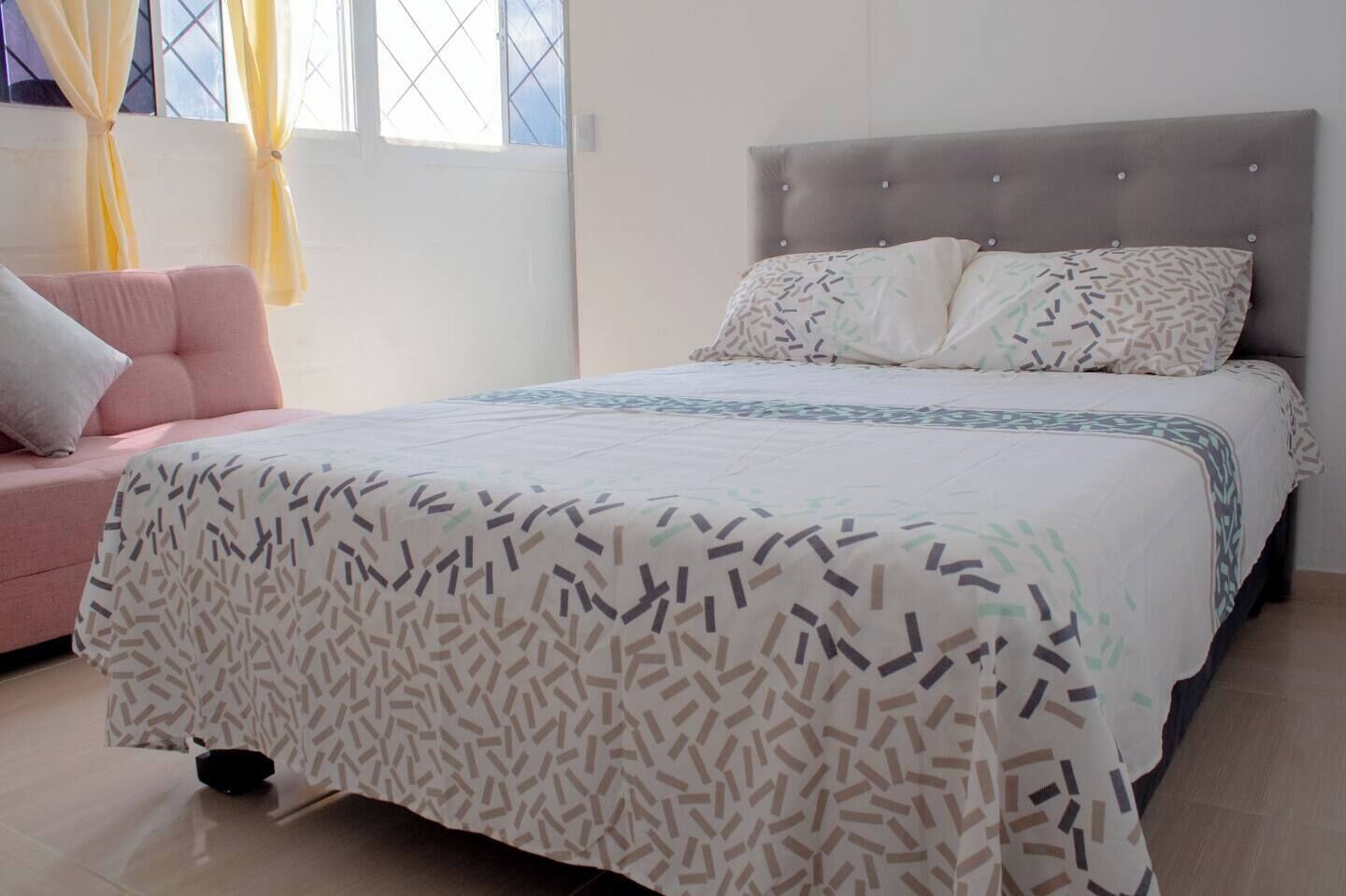 Un dormitorio con cama, sofá y ventana con cortinas.