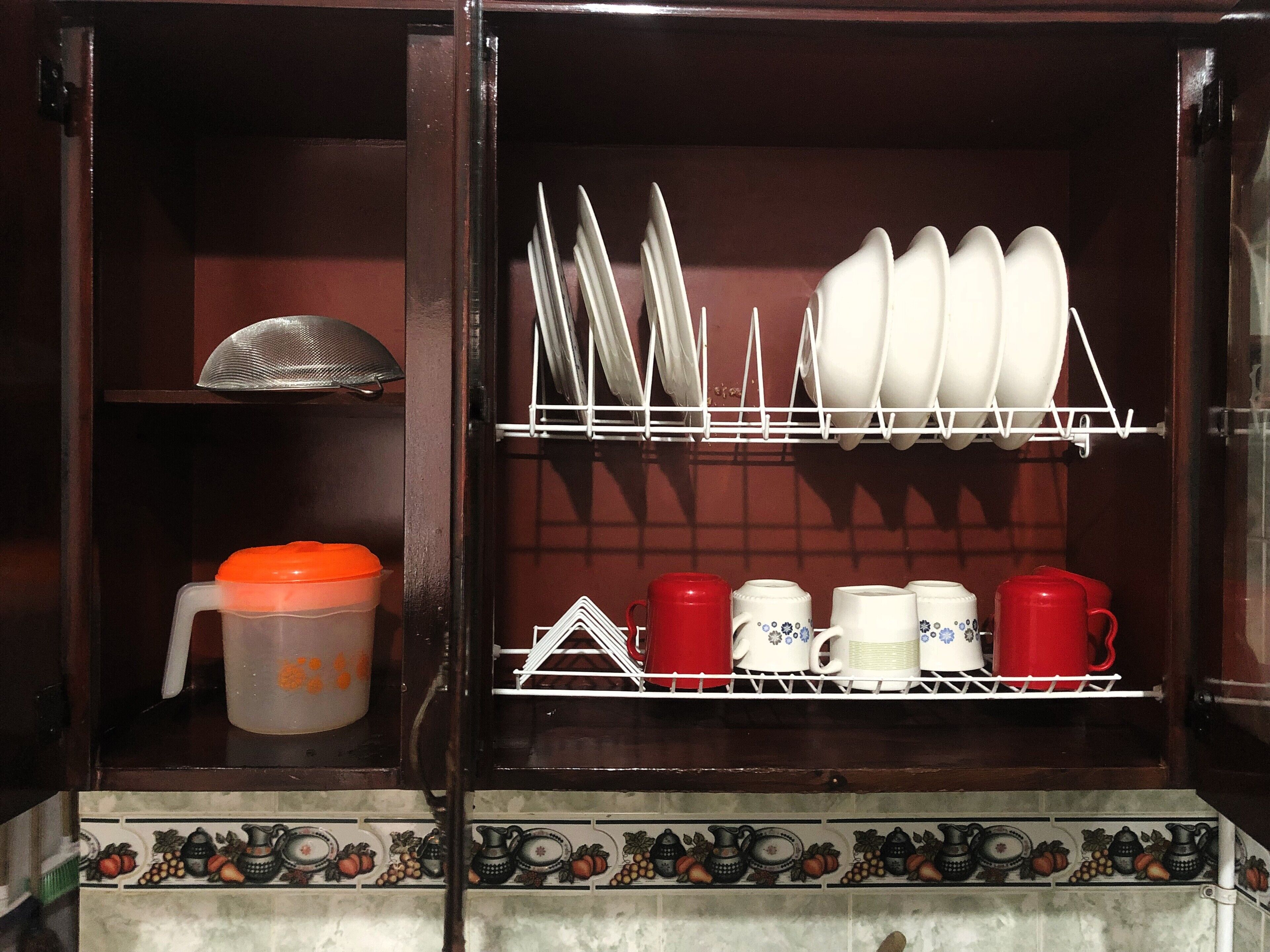 Un armario de cocina con estantes que contienen platos, tazas y un recipiente.