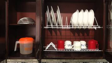 Un armario de cocina con estantes que contienen platos, tazas y un recipiente.