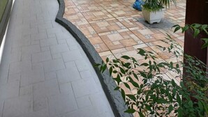A covered outdoor area with a curved pathway, outdoor seating, and potted plants. - Pousada Sol e Lua (Caraguatatuba)
