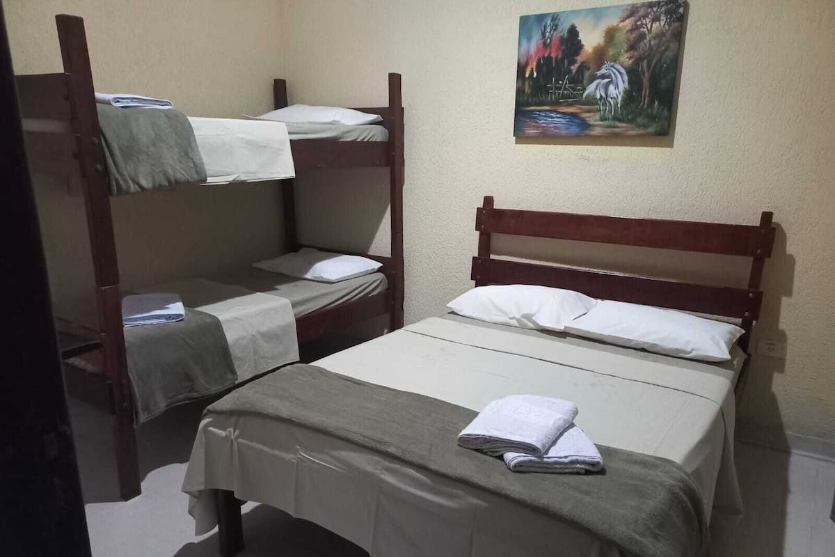 Ein Zimmer mit zwei Etagenbetten und einem Einzelbett, jeweils mit weißer Bettwäsche.