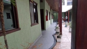 A covered corridor with a tiled floor, green walls, and windows. - Pousada Sol e Lua (Caraguatatuba)