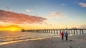 A pier extending into the sea with people walking along it. - Enjoy beachside vibes at beautiful Henley Beach! (Henley Beach)