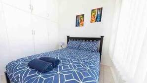 A bedroom with a bed, a wardrobe, and two wall-mounted artworks. - Enjoy beachside vibes at beautiful Henley Beach! (Henley Beach)