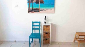 A room with a blue chair, a white cabinet with wicker baskets, and a painting of a beach scene. - Enjoy beachside vibes at beautiful Henley Beach! (Henley Beach)
