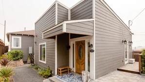 A two-story house with a front porch, a wooden door, and a small bench. - Savor the Peace at a Comfy Cottage Minutes from Downtown SF (Myrtle Beach)