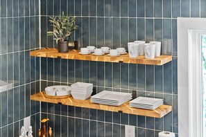 A kitchen with two wooden shelves holding white cups, plates, and a potted plant. - Luxury Lake Barkley Bungalow
 (Cadiz)