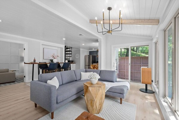 A modern living room with a grey sectional sofa, a wooden coffee table, and a chandelier.