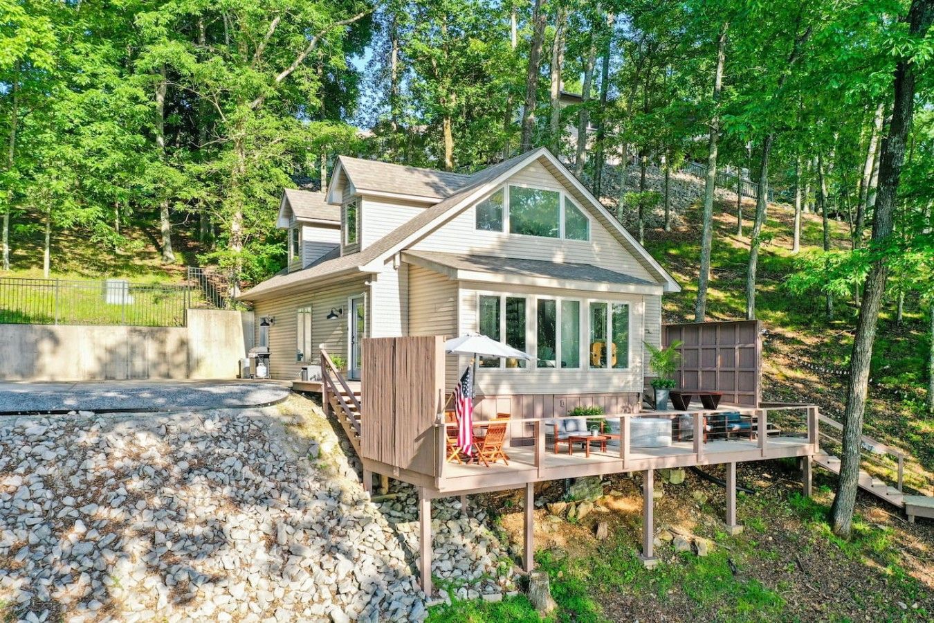 A two-story house with a deck, surrounded by trees.