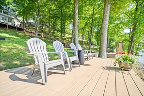 A deck with Adirondack chairs, a trash can, and a planter with flowers. - Luxury Lake Barkley Bungalow
 (Cadiz)