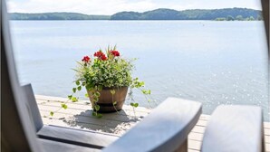 A wooden deck with a potted plant and a view of a calm lake.