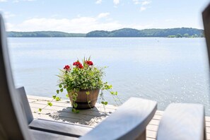 A wooden deck with a potted plant and a view of a calm lake.