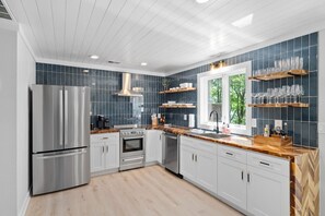 A modern kitchen with stainless steel appliances, wooden countertops, and blue-tiled backsplash.