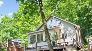 A house with a deck, a covered outdoor seating area, and a flag.