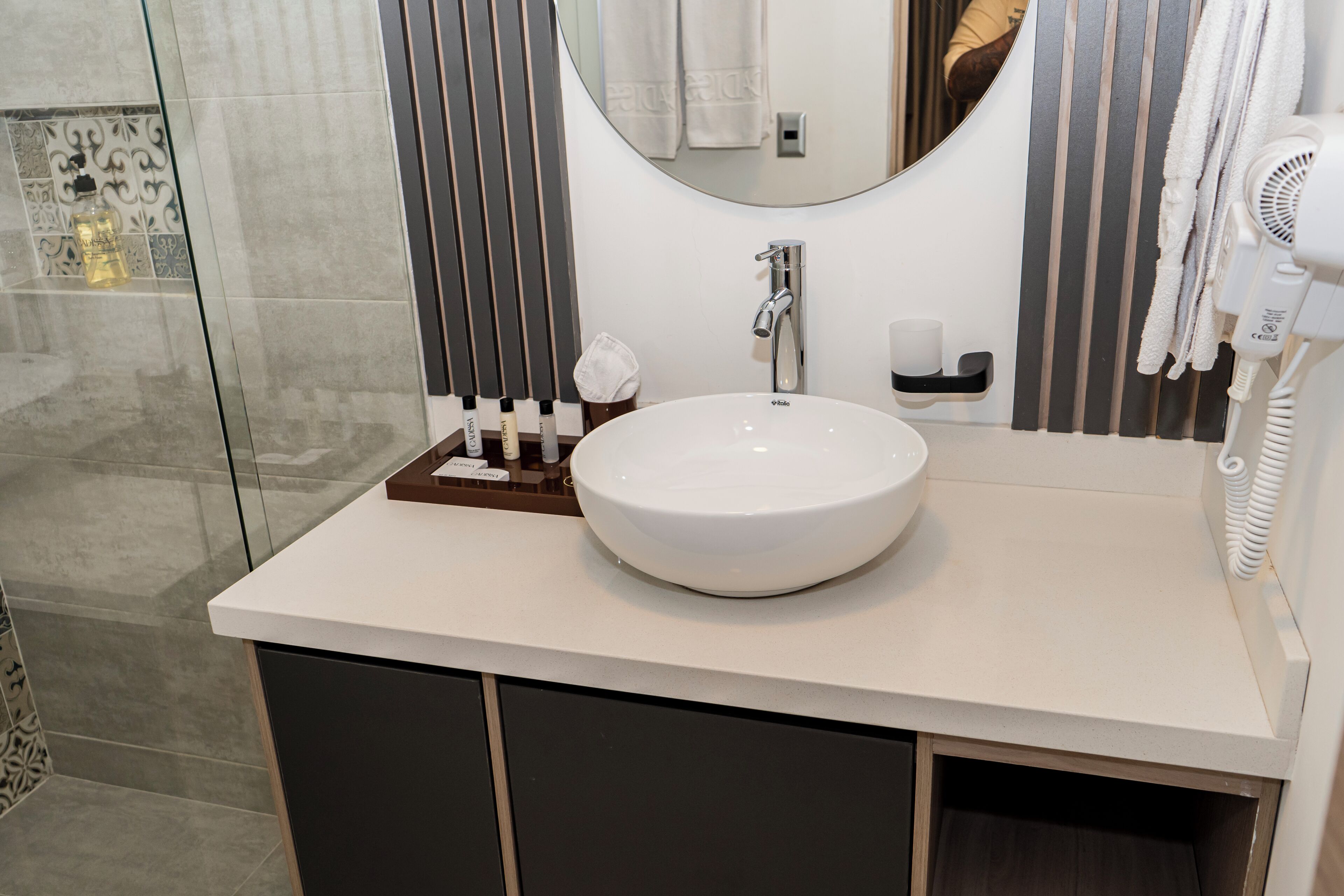 A modern bathroom with a large white sink, a mirror, a towel rack, and a hairdryer.