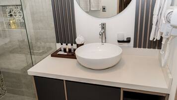 A modern bathroom with a large white sink, a mirror, a towel rack, and a hairdryer.