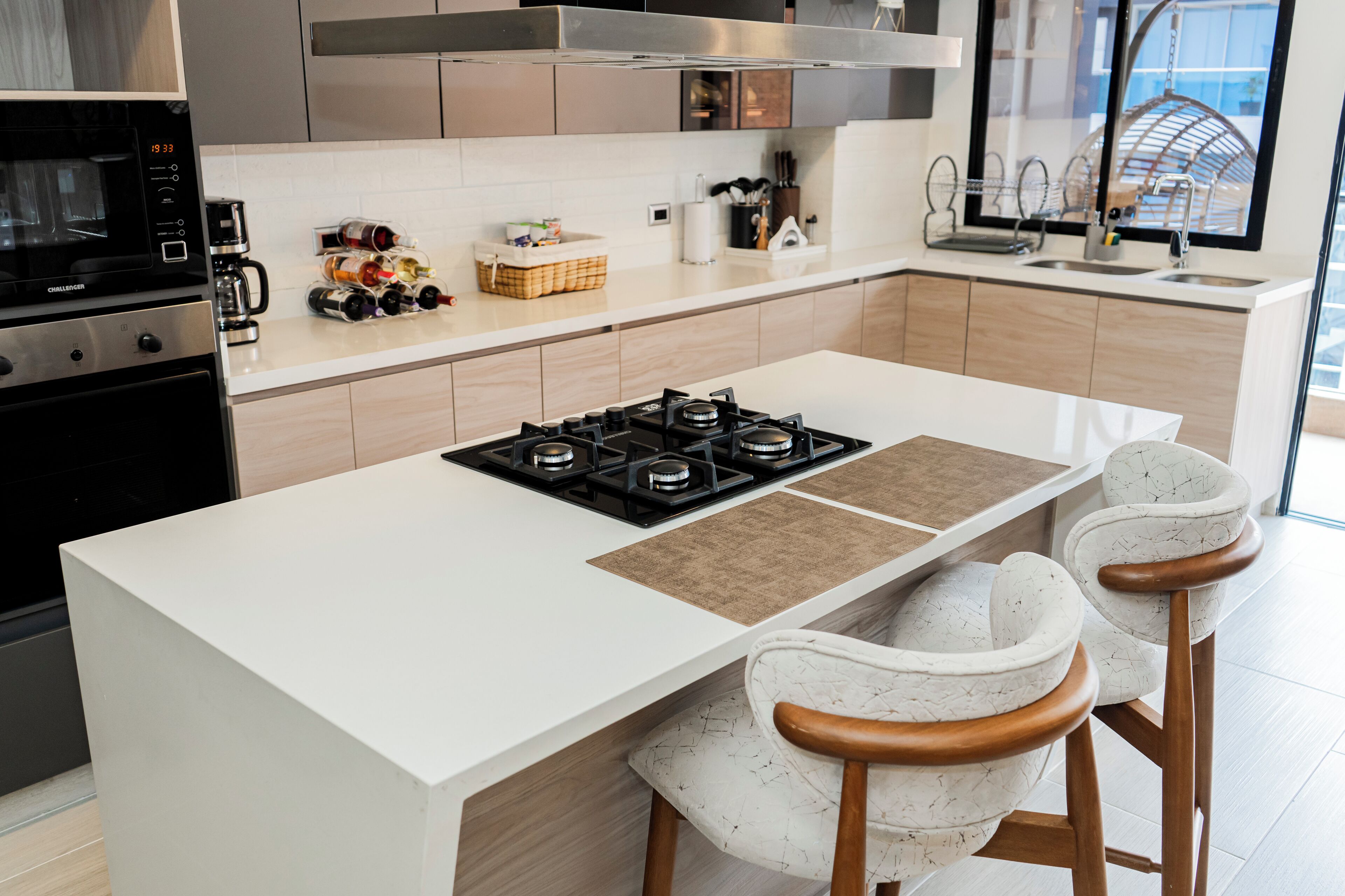 Una cocina moderna con una isla central, electrodomésticos de acero inoxidable y taburetes de bar.