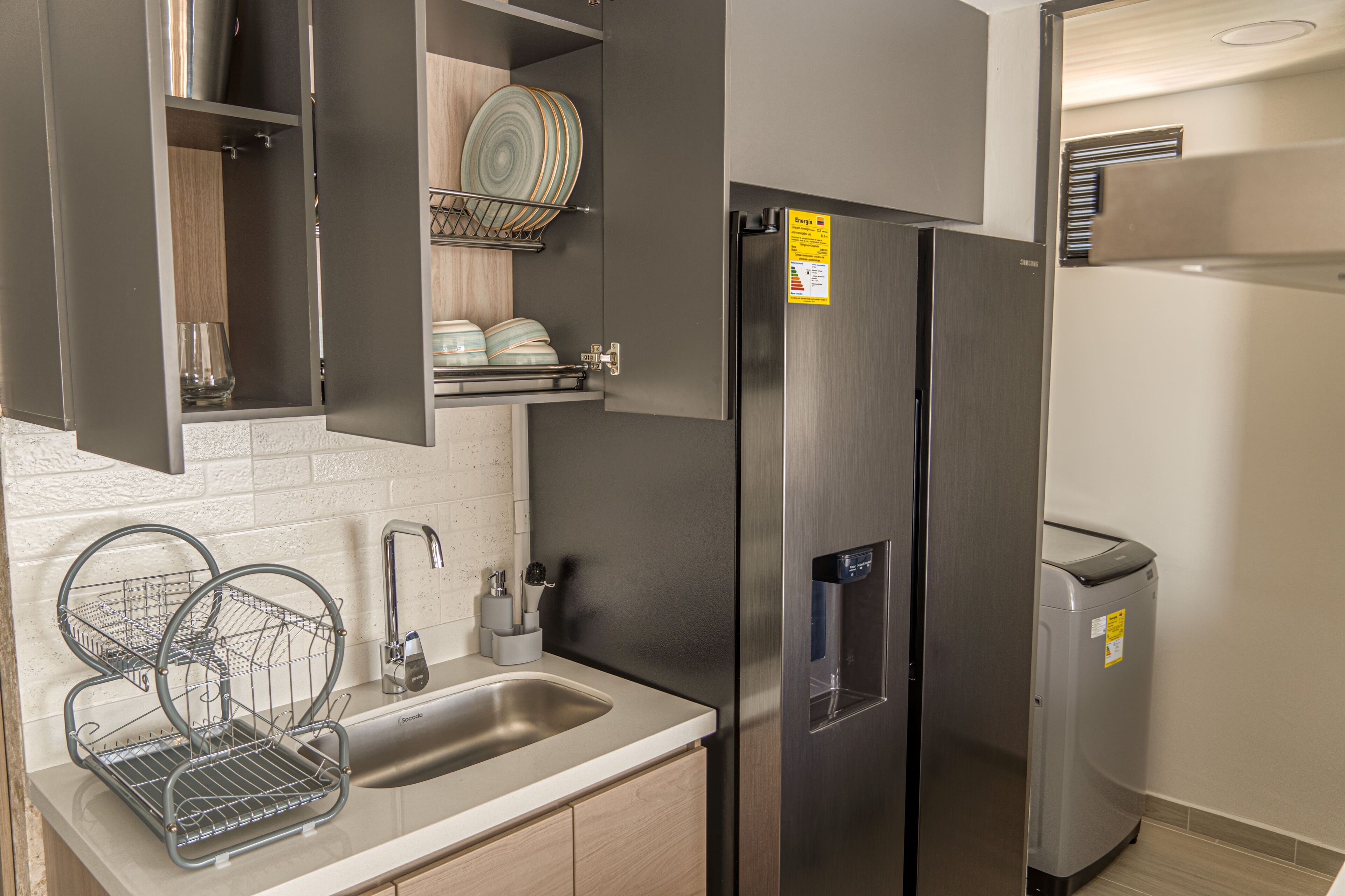 A modern kitchen with a stainless steel refrigerator, a built-in dishwasher, and a double sink.