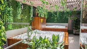 Une pièce avec deux lits en bois, une armoire en bois et de nombreuses plantes vertes luxuriantes.