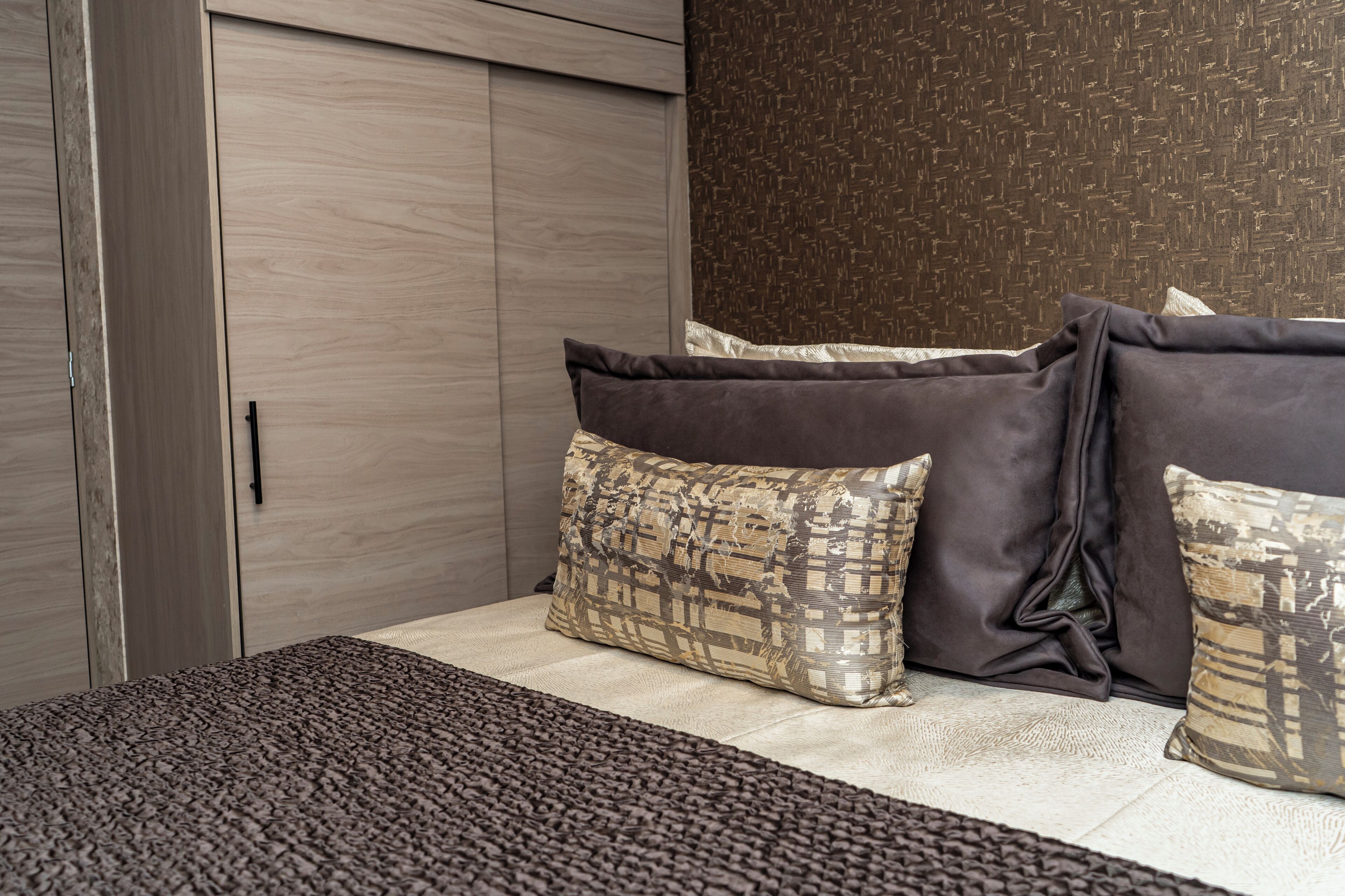 A bedroom with a bed, pillows, and a wardrobe.