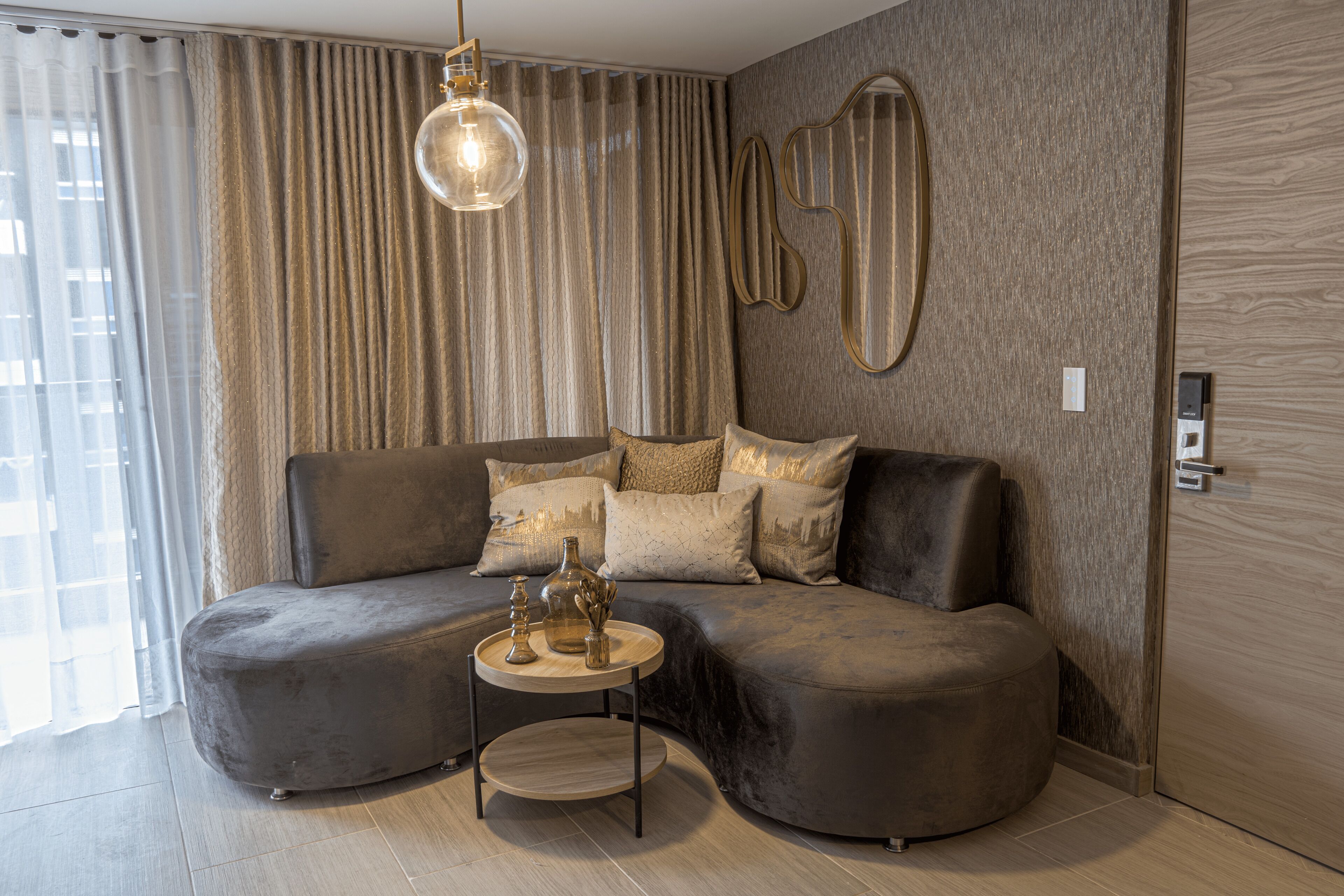 A modern living room with a curved sofa, a small round table, and a pendant light.